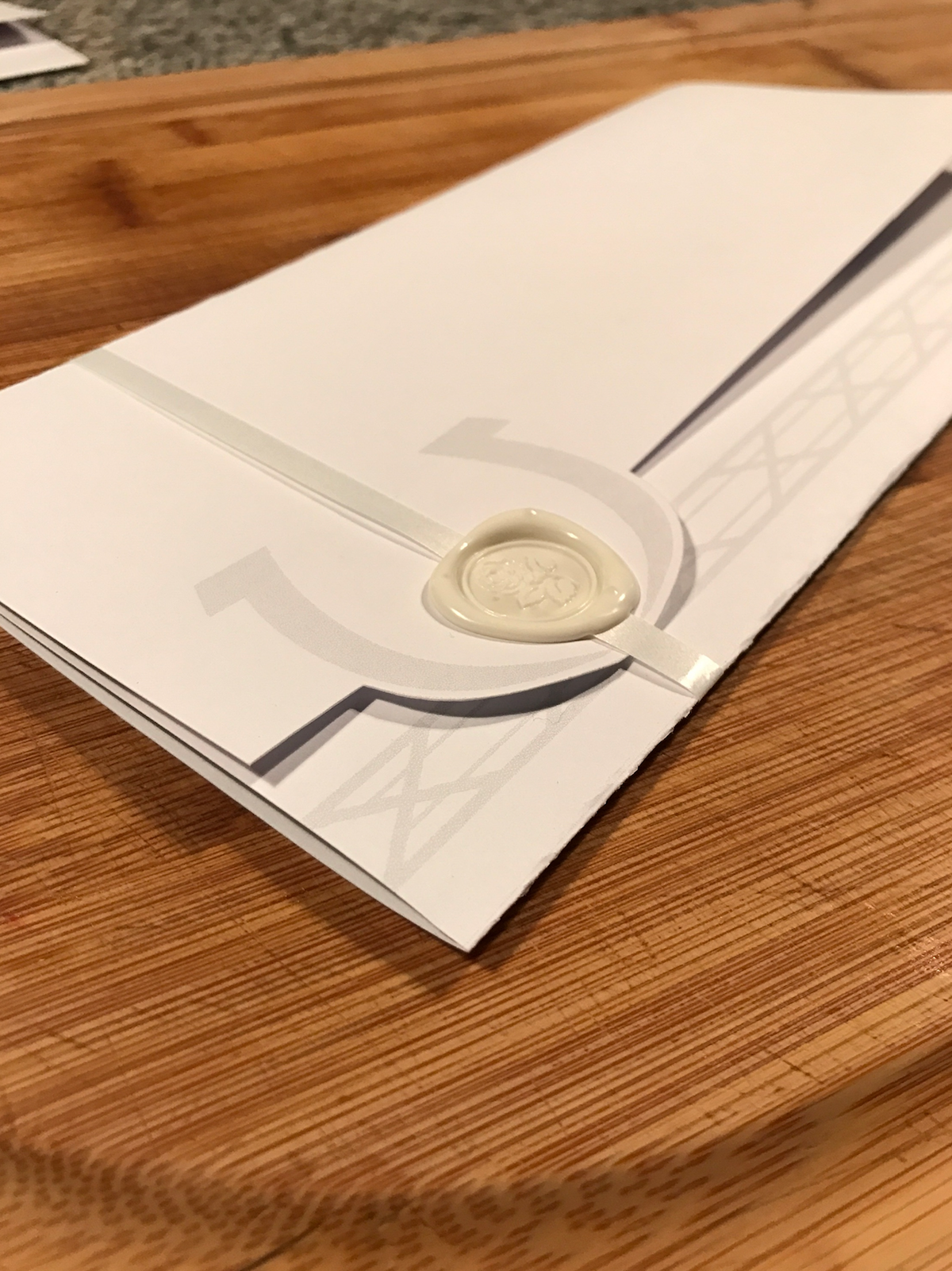 Detail of sealed envelope with custom rose wax seal and satin ribbon closure