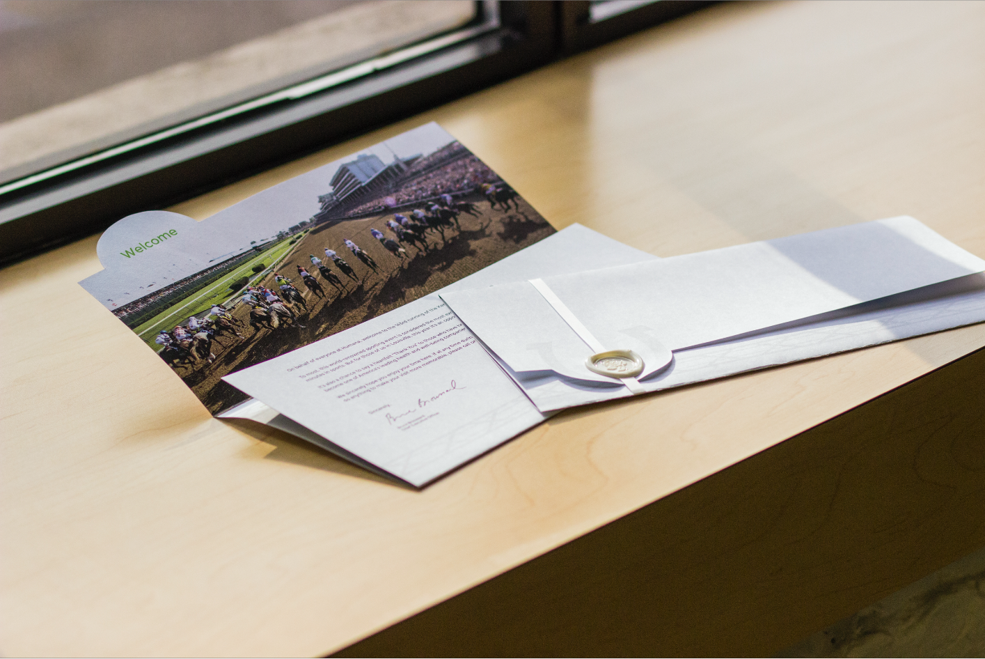 Invitation opened showing Welcome booklet with Churchill Downs photography and personalized letter